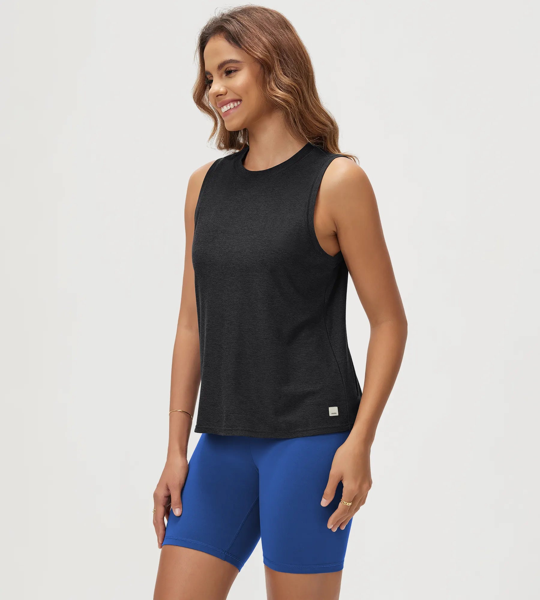 ODODOS Stratum Women's Performance Tank in black with blue workout wear shorts.